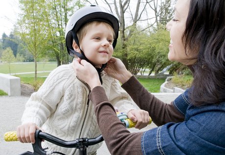 Mutter sichert Sohn den Fahrradhelm