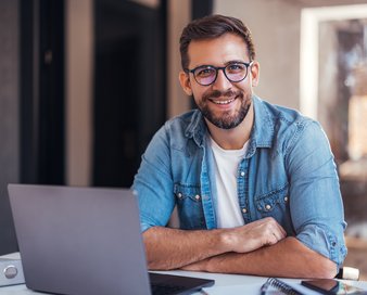 Mann in Jeanshemd vor Laptop